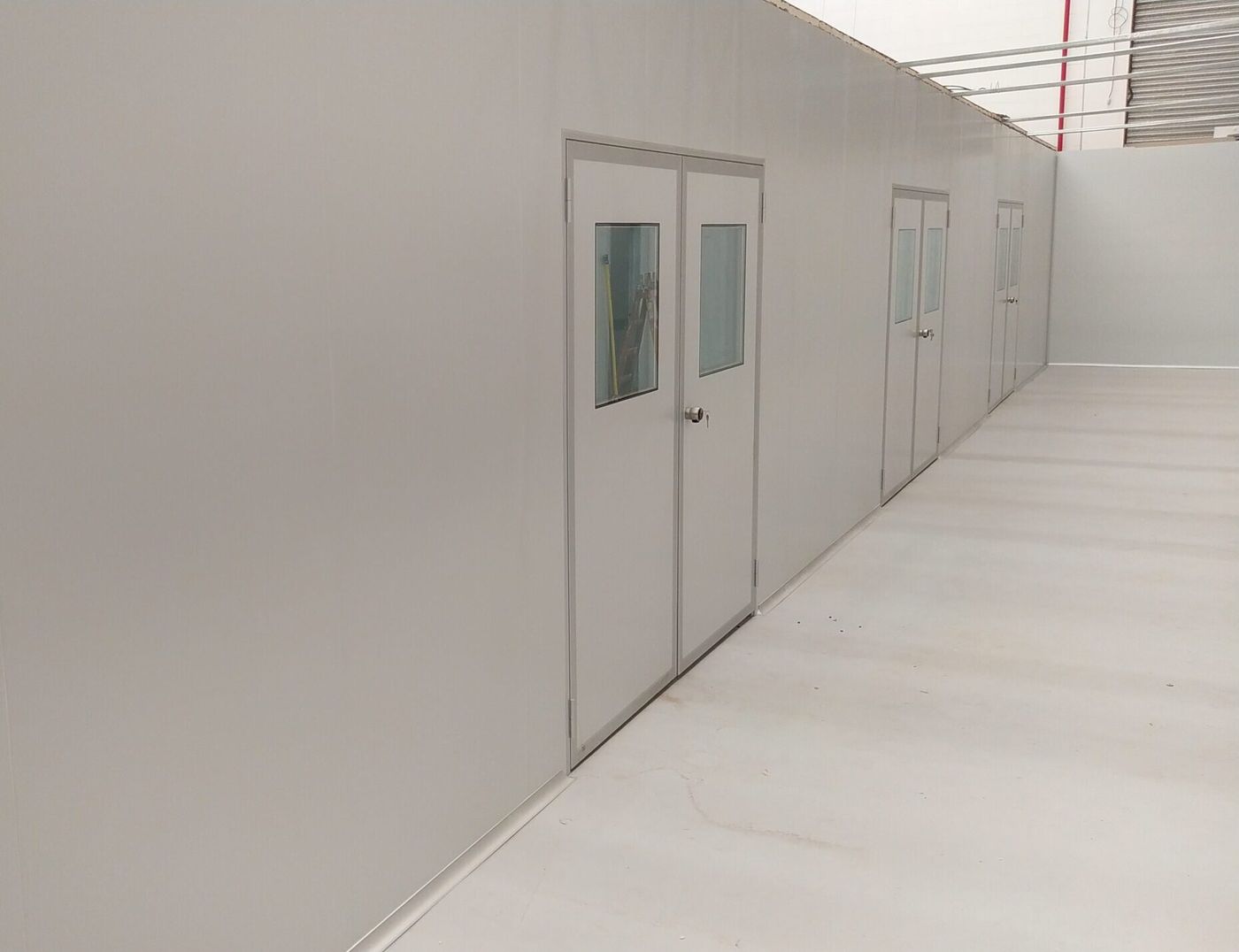Pasillo de sala limpia con puertas de doble contacto y visores